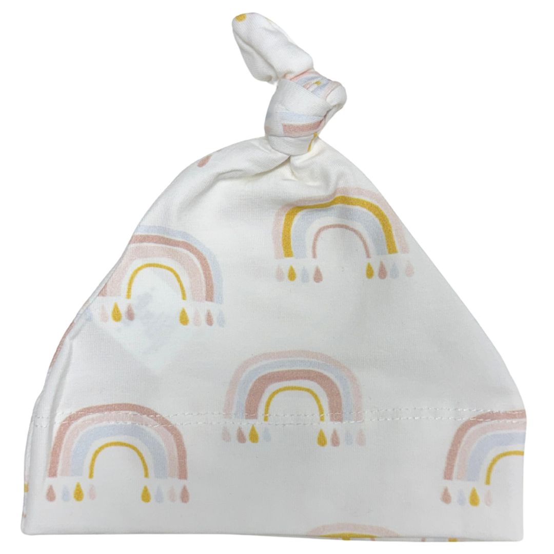 A white baby beanie hat with a knotted top and an all-over pastel rainbow pattern